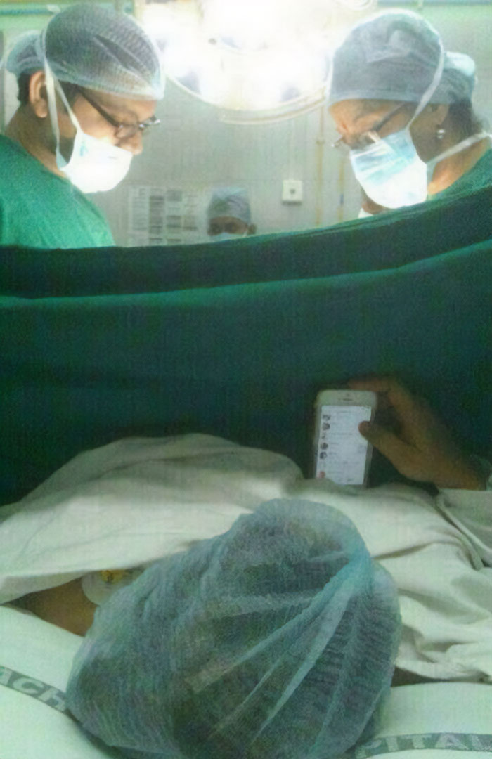 People in surgical attire, a patient holds a phone, creating a moment that makes you go 'hmmm'.