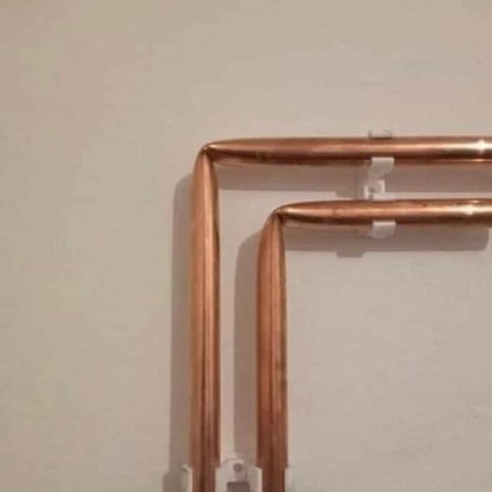 Copper pipes bent at right angles on a wall, making people go "hmmm" with their unusual alignment.