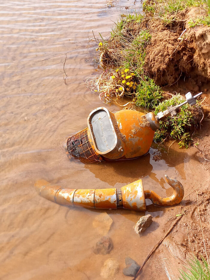 Rusty industrial equipment partly submerged in water, evoking a 'hmmm' reaction with its unusual placement and weathered appearance.
