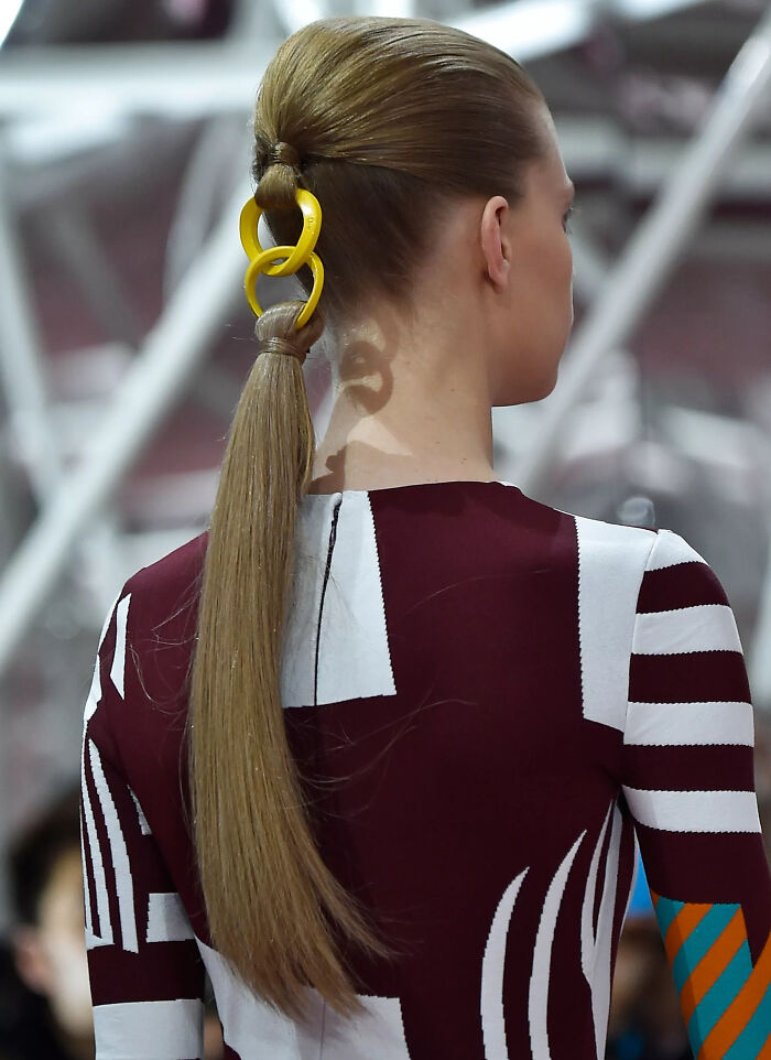 Hairstyle with yellow chain accessory creates a 'hmmm' moment, worn by a person in a patterned outfit.