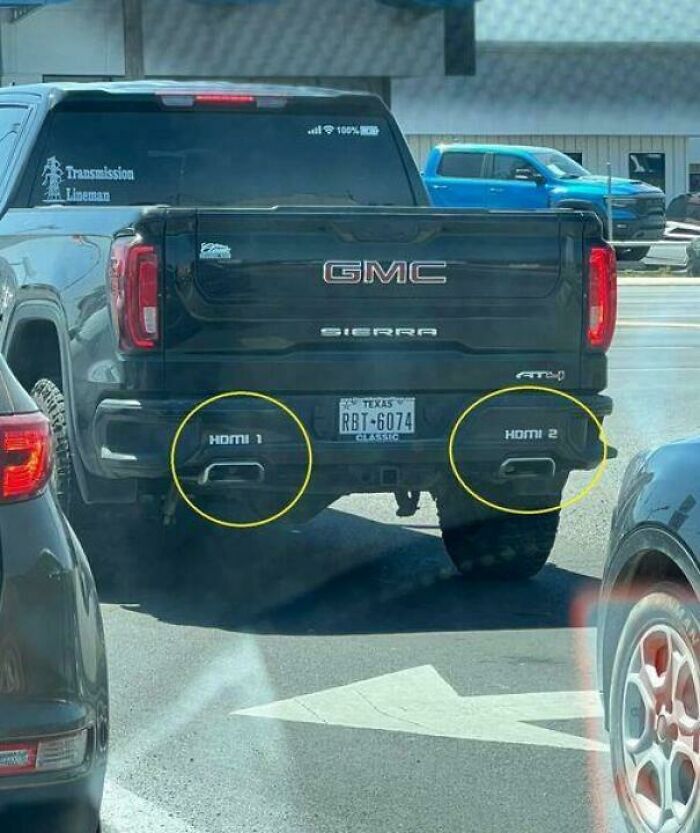 GMC Sierra with exhaust pipes labeled as HDMI 1 and HDMI 2, a humorous sight in traffic.