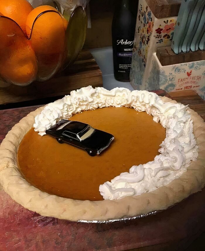 Pie with a toy car partially covered in whipped cream, creating a 'hmmm' moment.